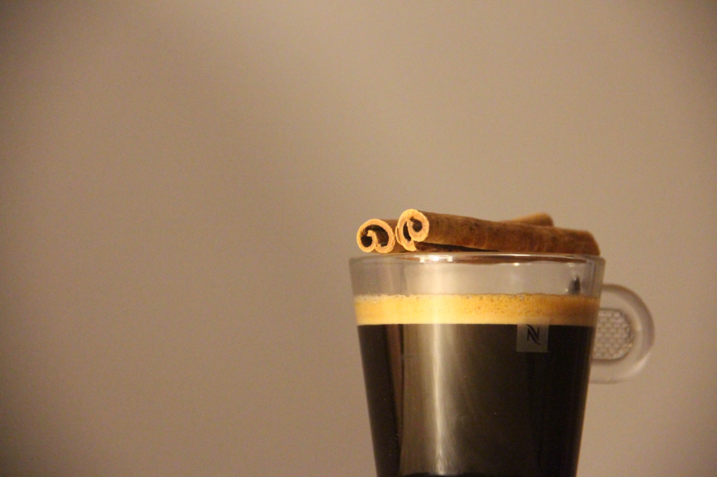 A Nespresso coffee with cinnamon sticks on top.