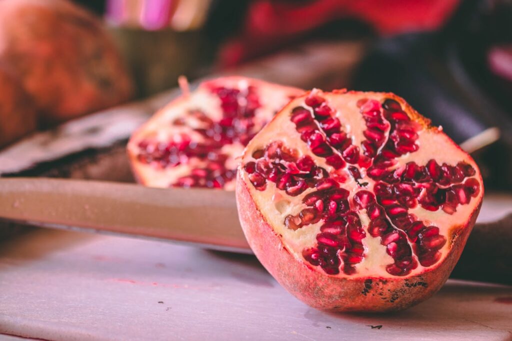 Close-up of a halved pomegranate, showcasing vibrant red seeds arranged in a star-like pattern.
