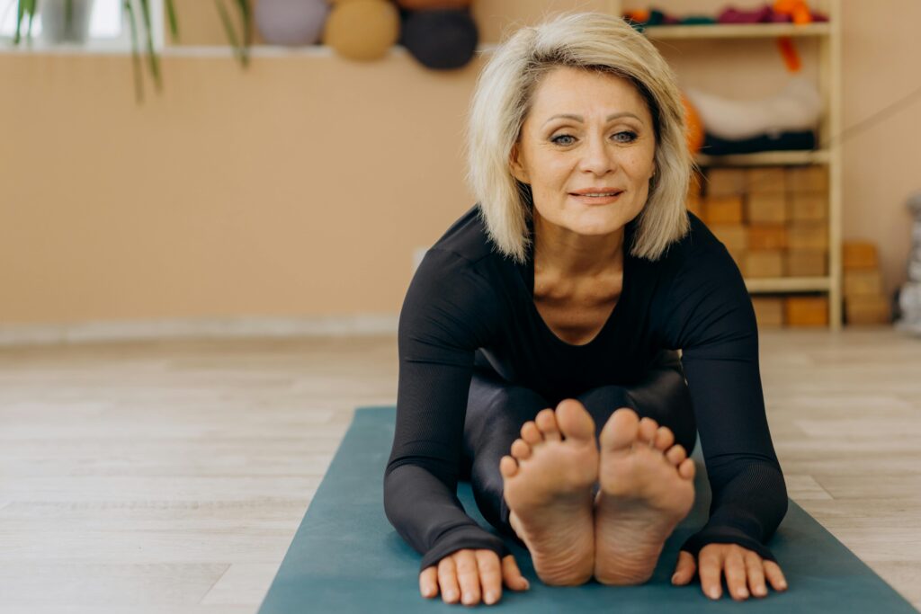 Senior woman practicing yoga indoors on a blue yoga mat.