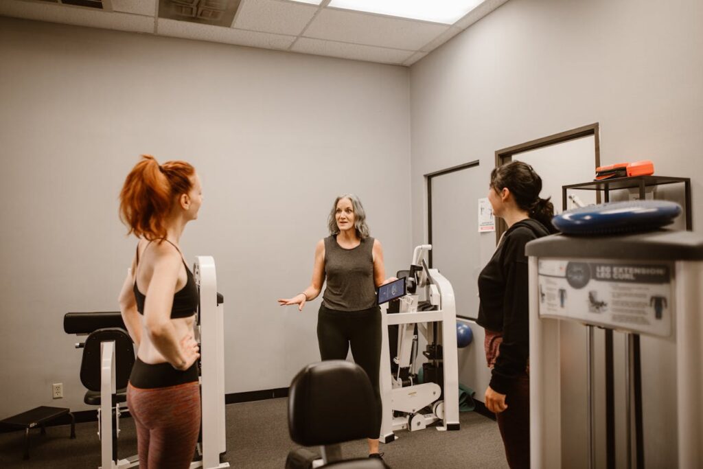 Three women in the gym having a chat, with exercise equipment in the background.