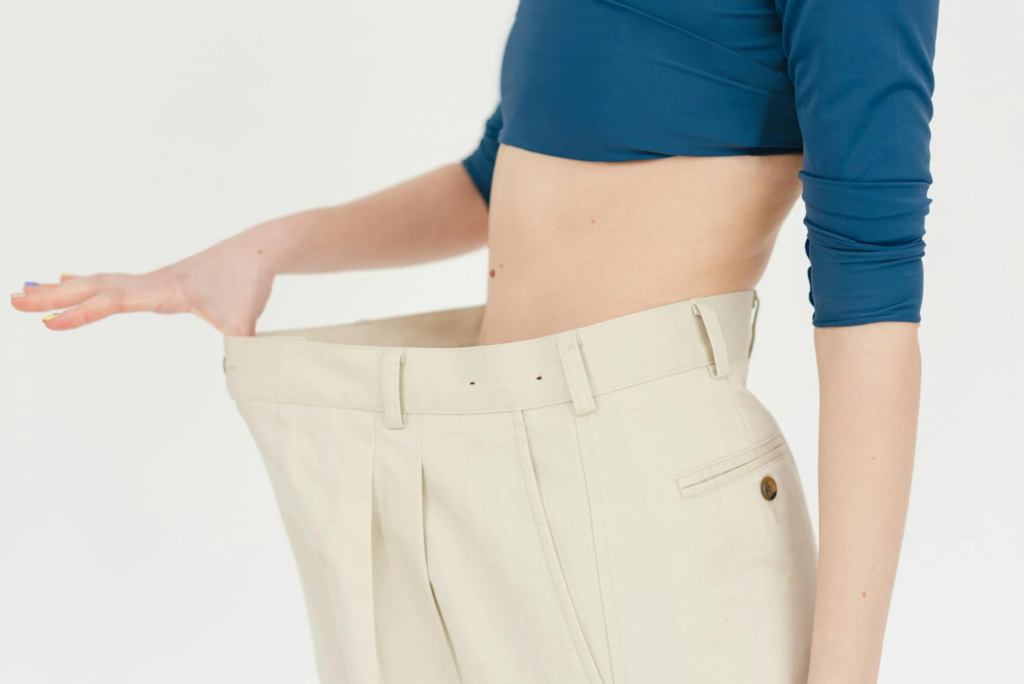 A woman in crop top and oversized showing off her slim waist.