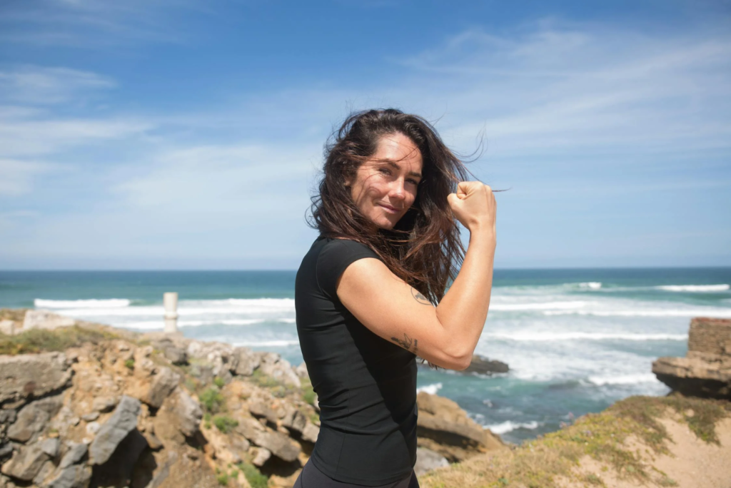 A woman in black top, clenching her fist, and showing off her biceps.