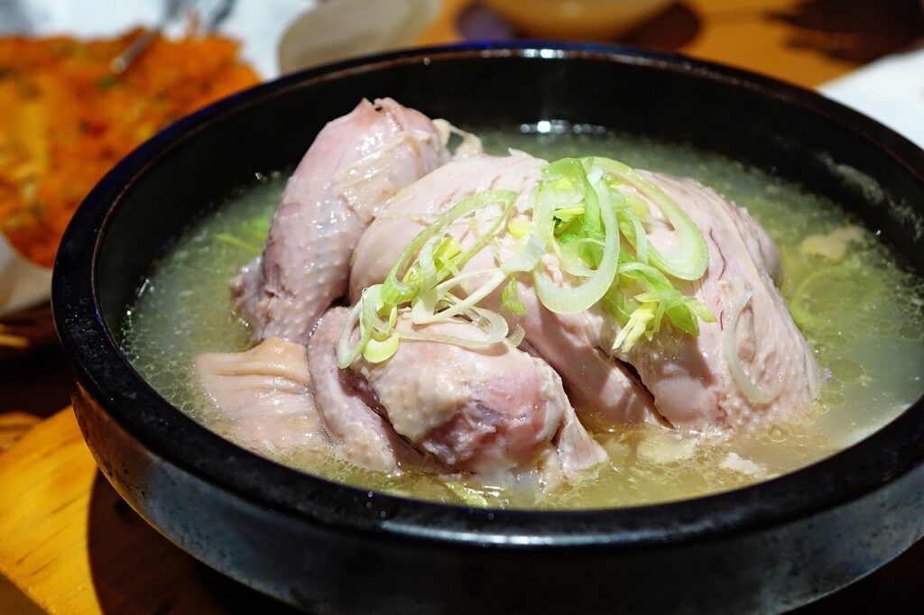 A bowl of traditional chicken soup, garnished with green onions.