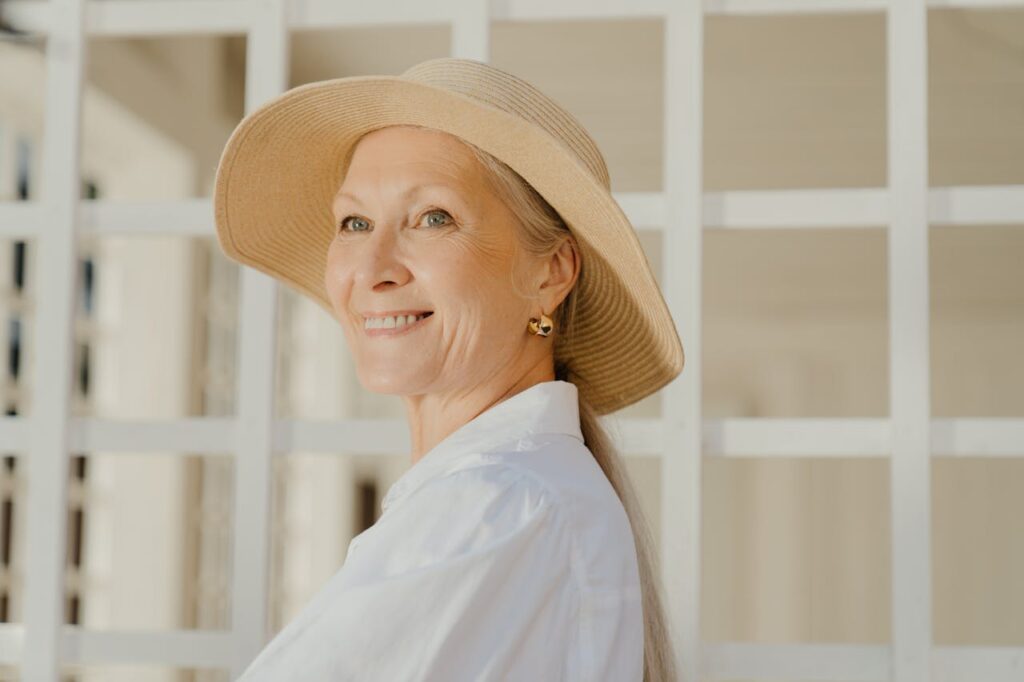 A smiling elderly woman wearing a wide-brimmed hat.