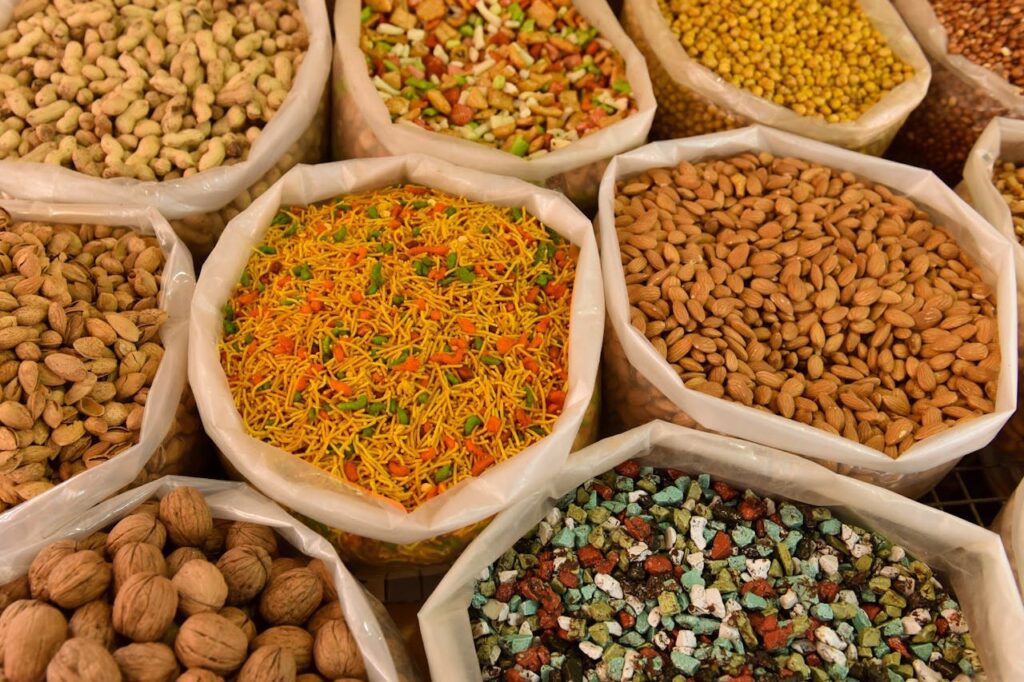 A variety of nuts and dried foods displayed in large sacks at a market.