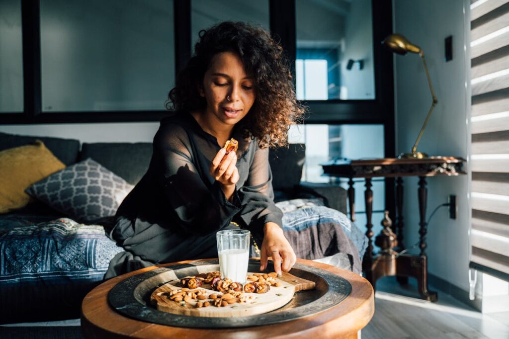 A woman sitting in a living room, enjoying a snack of nuts and dried fruit.