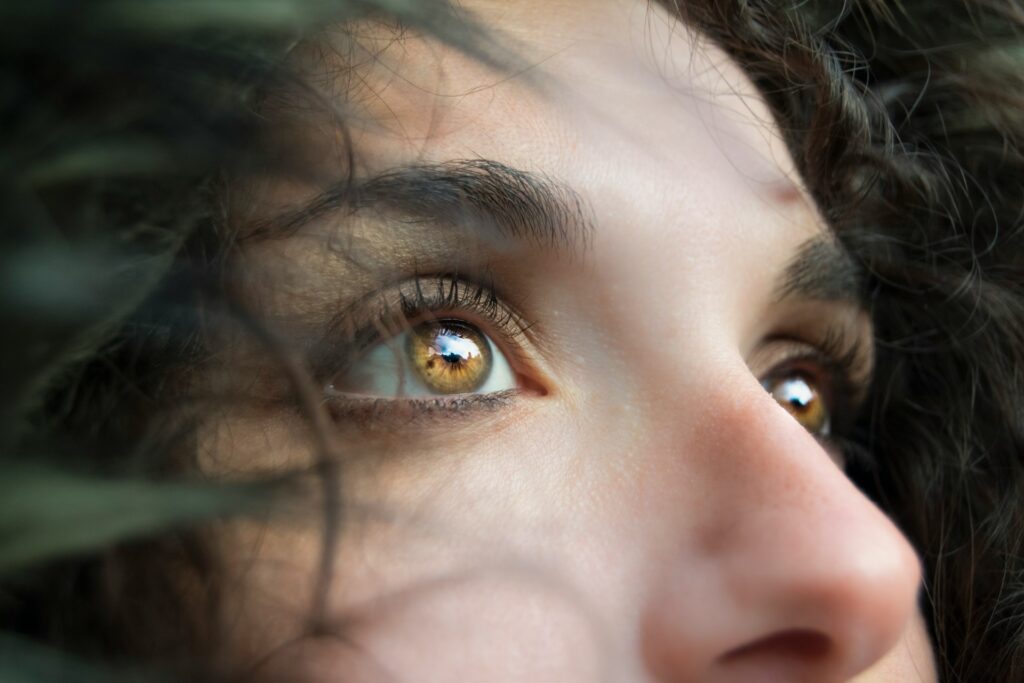 Close-up of a woman’s eyes with hazel irises, gazing upward with thoughtful expression.
