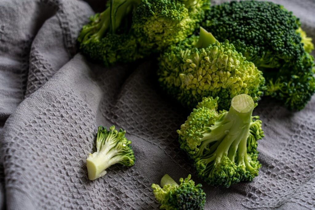 Fresh broccoli florets on a gray fabric.