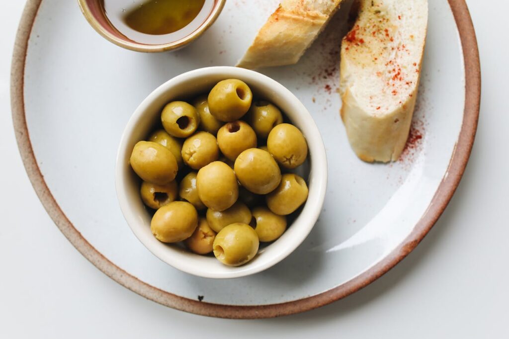 Green olives with slices of bread, ready to be enjoyed as a snack or appetizer.