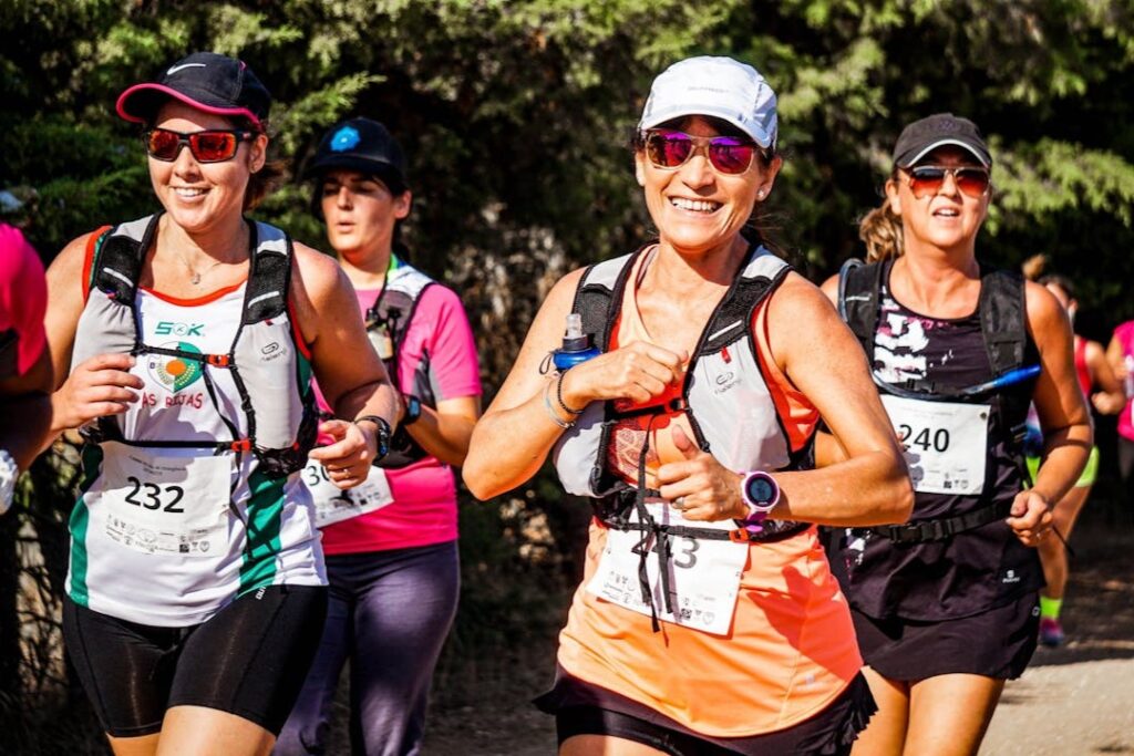 Group of women participating in a running event, smiling as they jog.