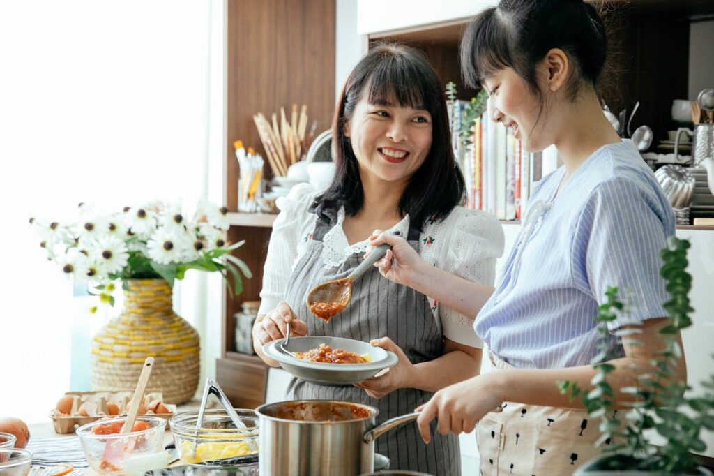 Mother and daughter cooking together in a bright kitchen.