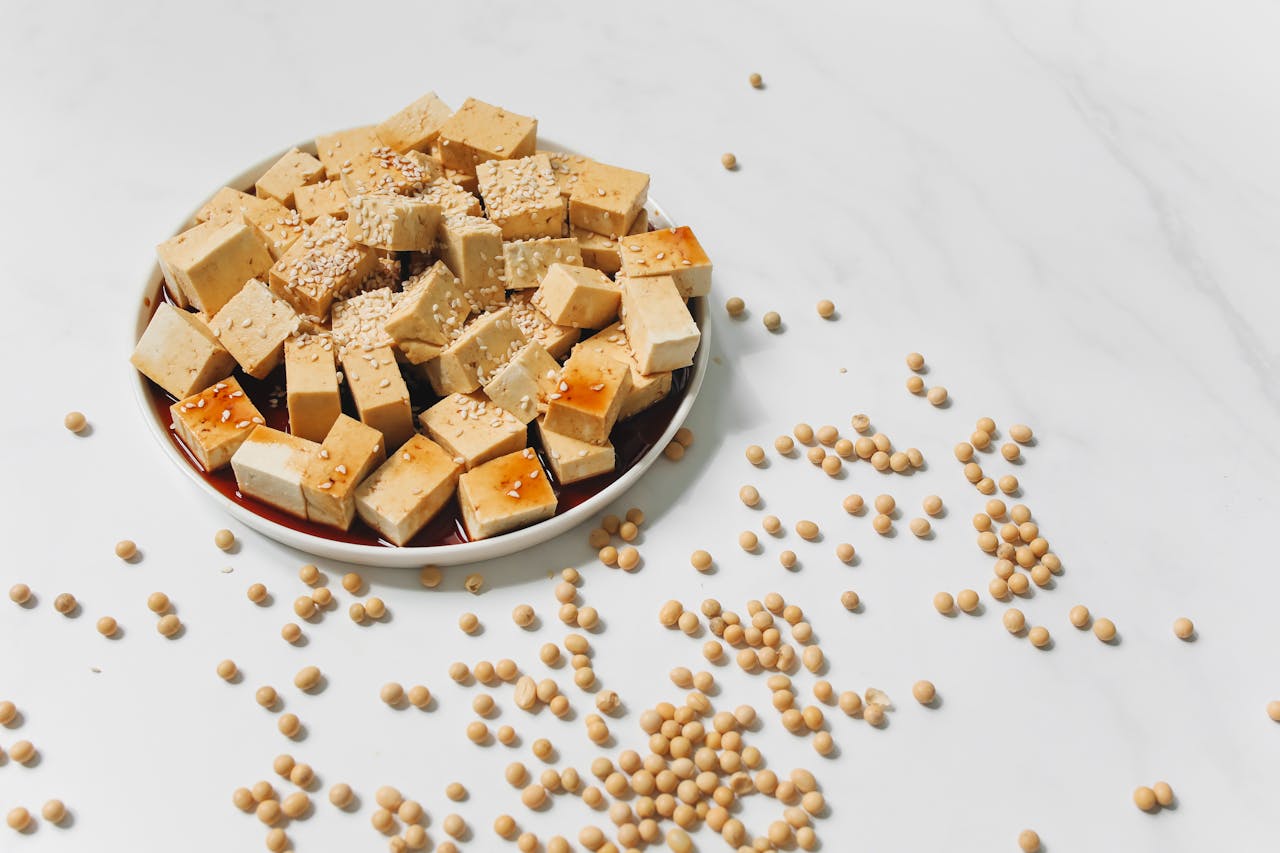 A plate of tofu cubes garnished with sesame seeds, with scattered soybeans around the plate.