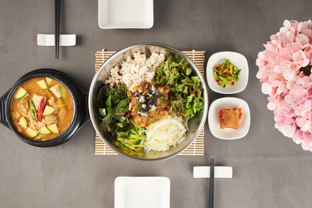 Bibimbap with vegetables, tofu, and a bowl of soup, including fermented side dishes like kimchi.