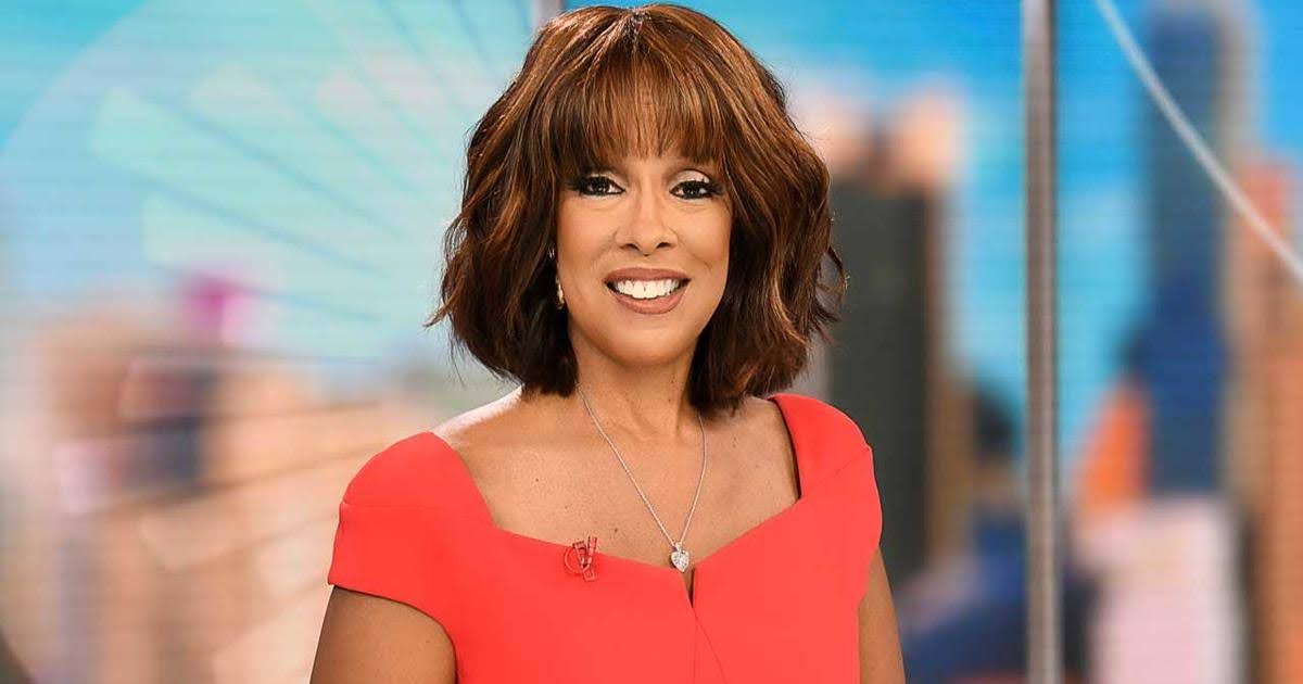 Gayle King in a studio setting, wearing a red dress and smiling.