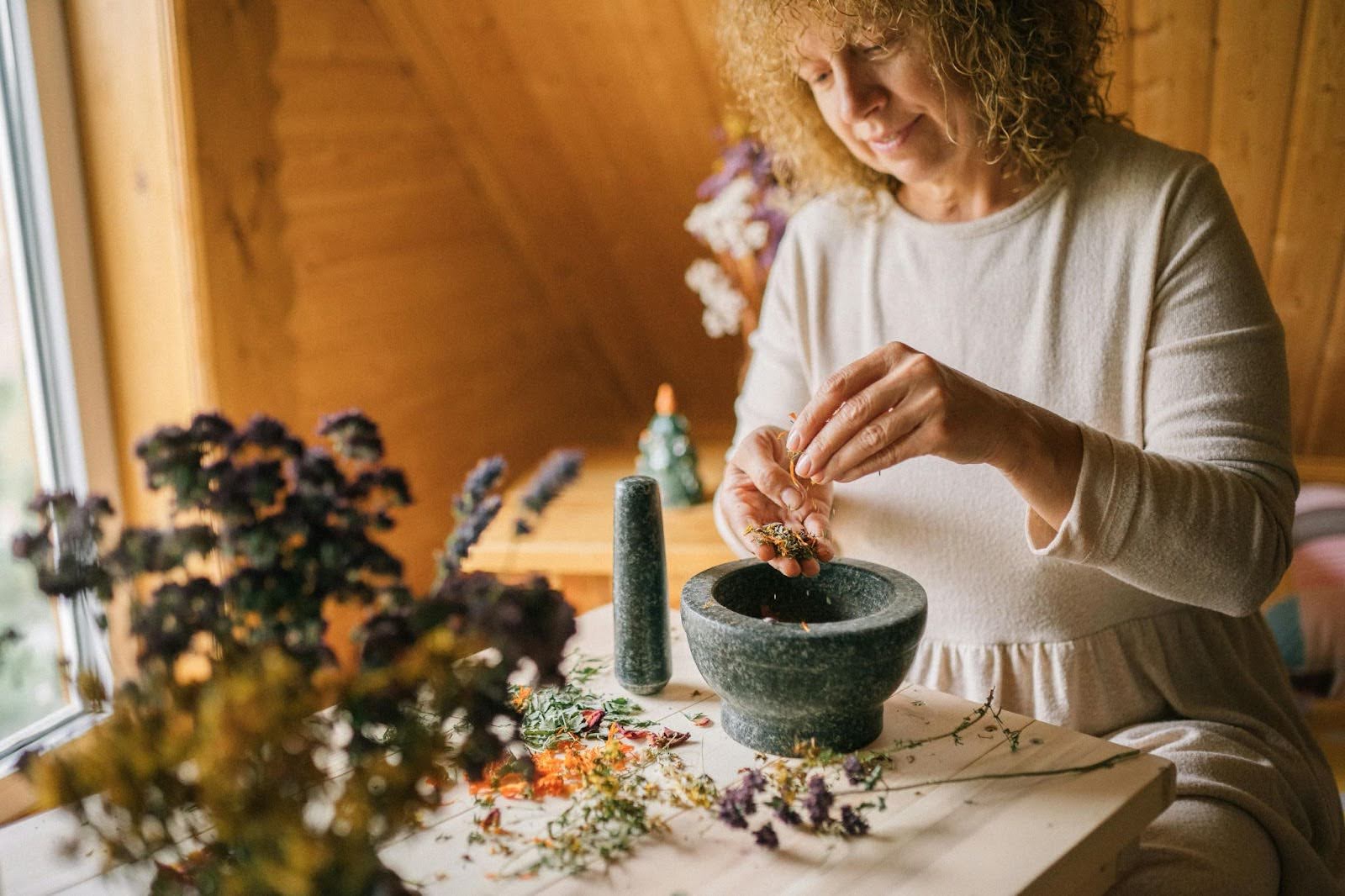A woman preparing herbs with a mortar and pestle, highlighting the use of Kava Kava for menopause and blood sugar management.