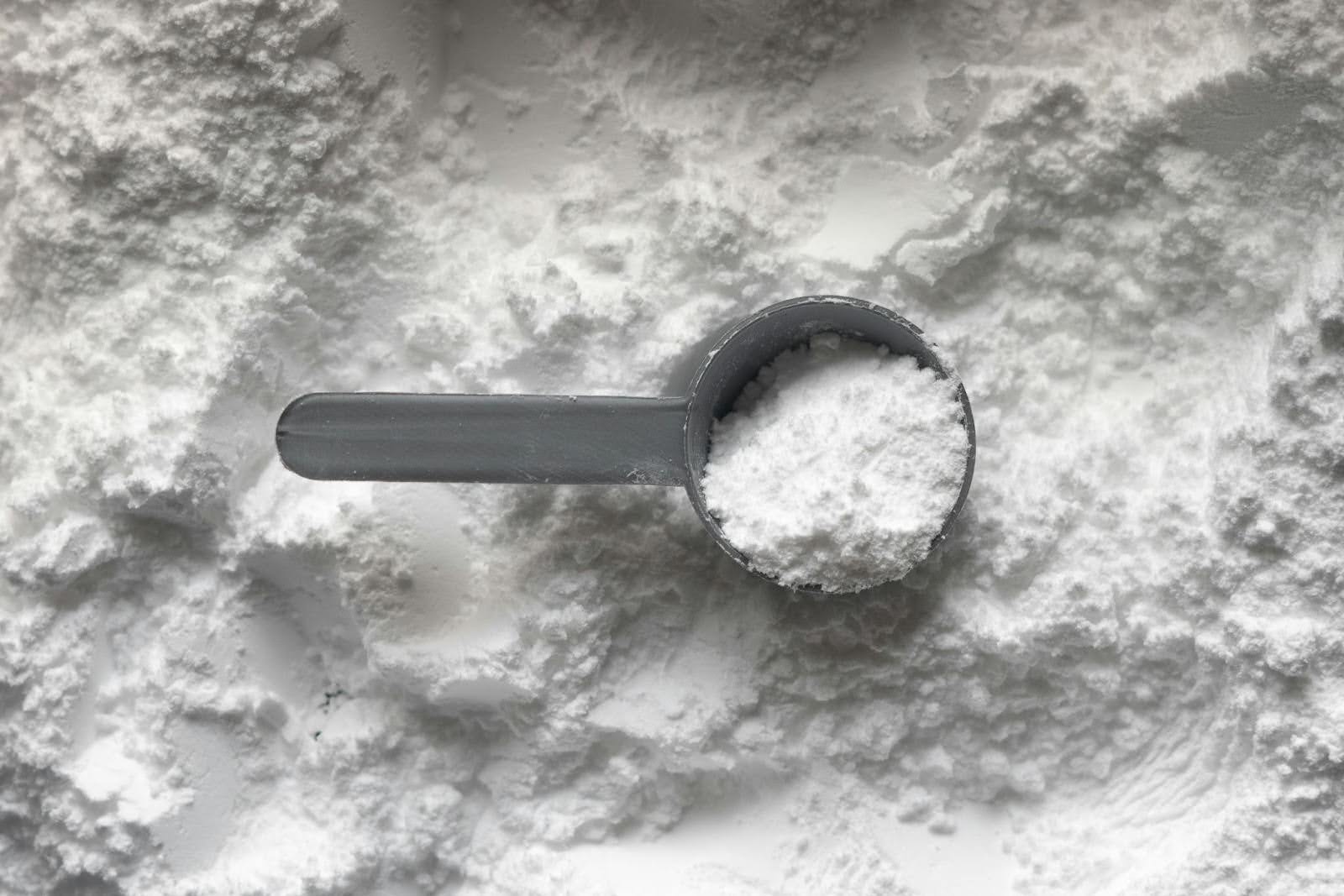 A scoop of L-lysine powder on a textured surface, used for supporting blood sugar regulation and weight loss during menopause.