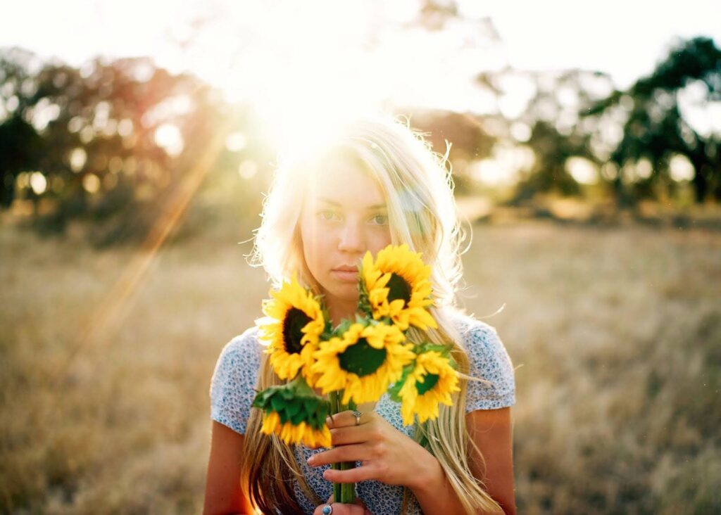 Woman holding a bouquet of sunflowers in a field, symbolizing the natural health benefits of sunflower lecithin for menopause.