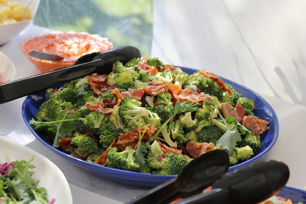 Bowl of broccoli salad with bacon pieces, served on a table.