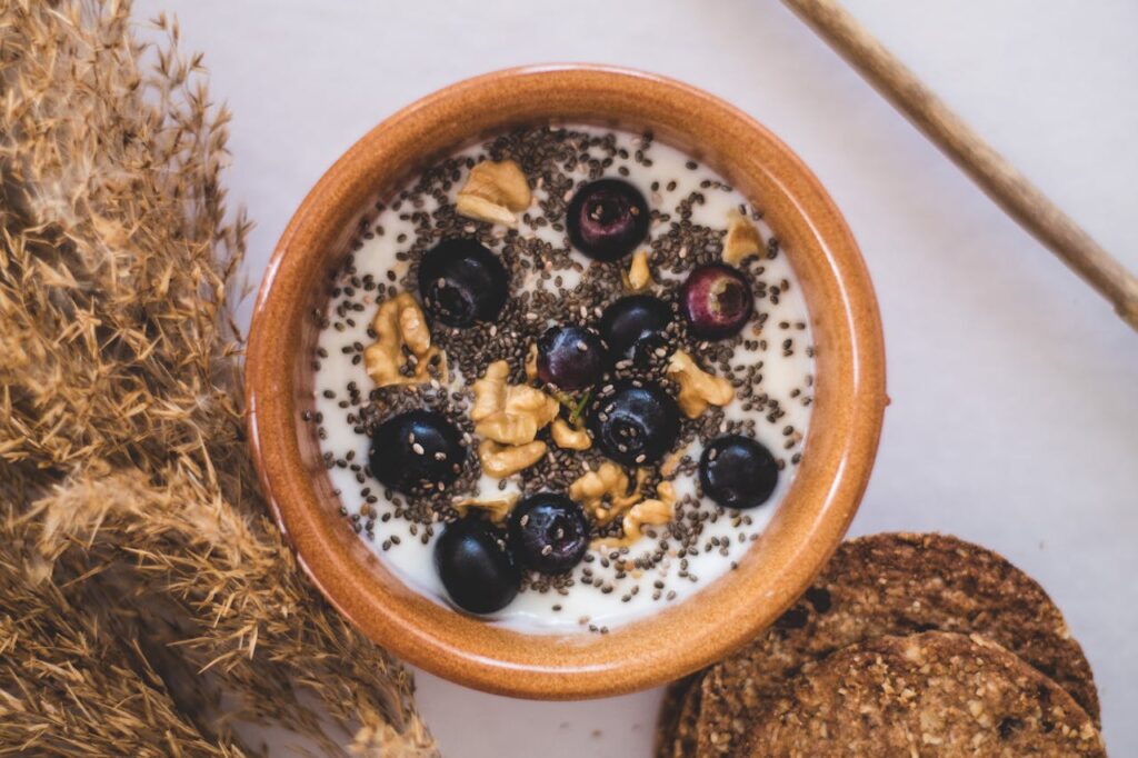Bowl of yogurt topped with chia seeds, walnuts, and blueberries.