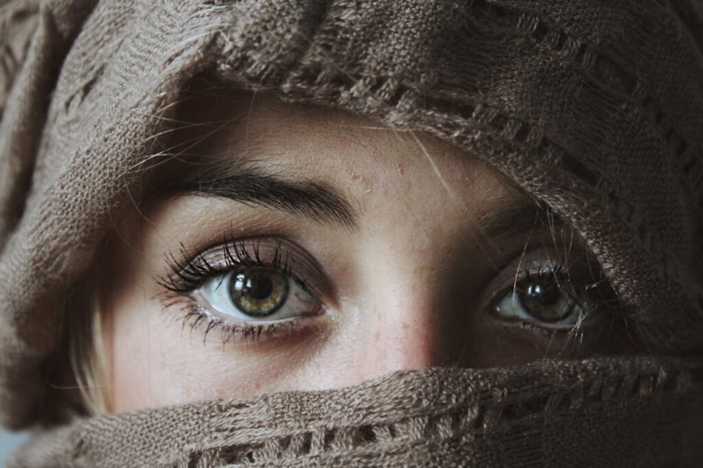 Close-up of a woman's eyes, partially covered by a brown fabric.