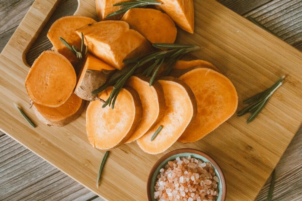 Freshly sliced sweet potatoes on a wooden cutting board.