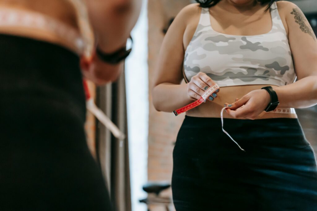 Woman measuring waist with a tape measure.